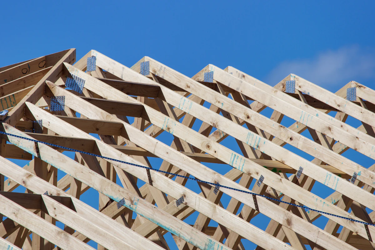 Fresh roof trusses of a new home rising against a blue sky